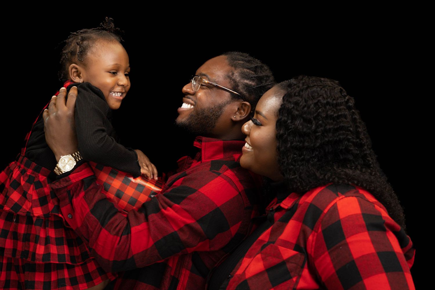 Joyful family in red plaid shirts laughing together during Christmas.