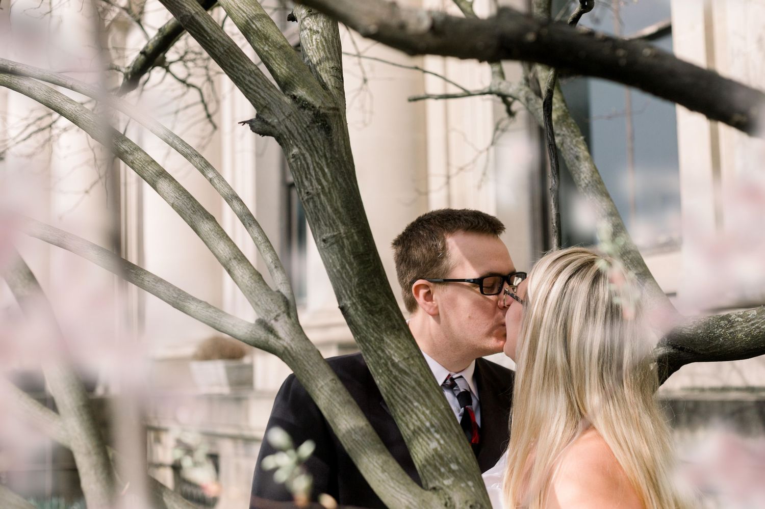 A romantic moment captured through tree branches with soft natural lighting.