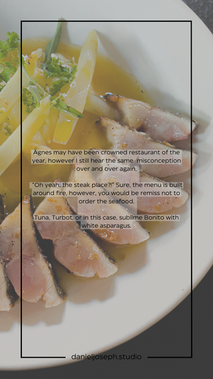 Seared tuna slices with white asparagus and fresh herbs in a light broth.