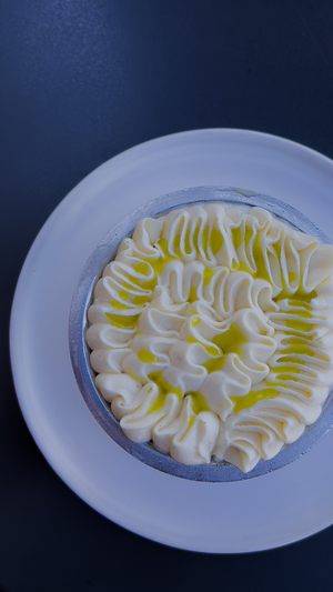A beautifully decorated dessert featuring white cream piping in a circular pattern with yellow highlights.