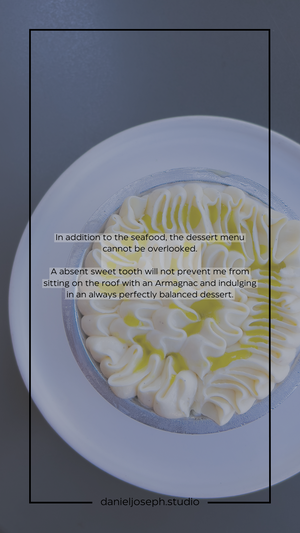 An elegantly piped dessert with white cream swirls and yellow accents on a pristine white plate.