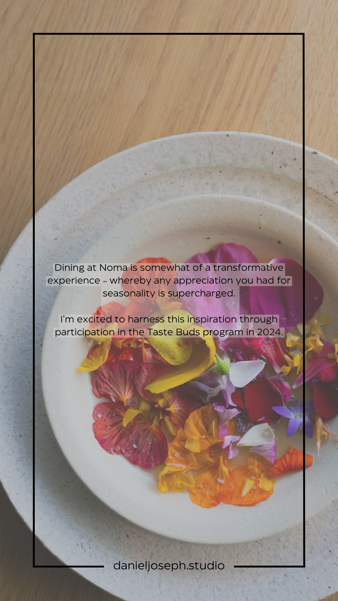 Vibrant edible flowers arranged on a speckled ceramic plate against a wooden surface.