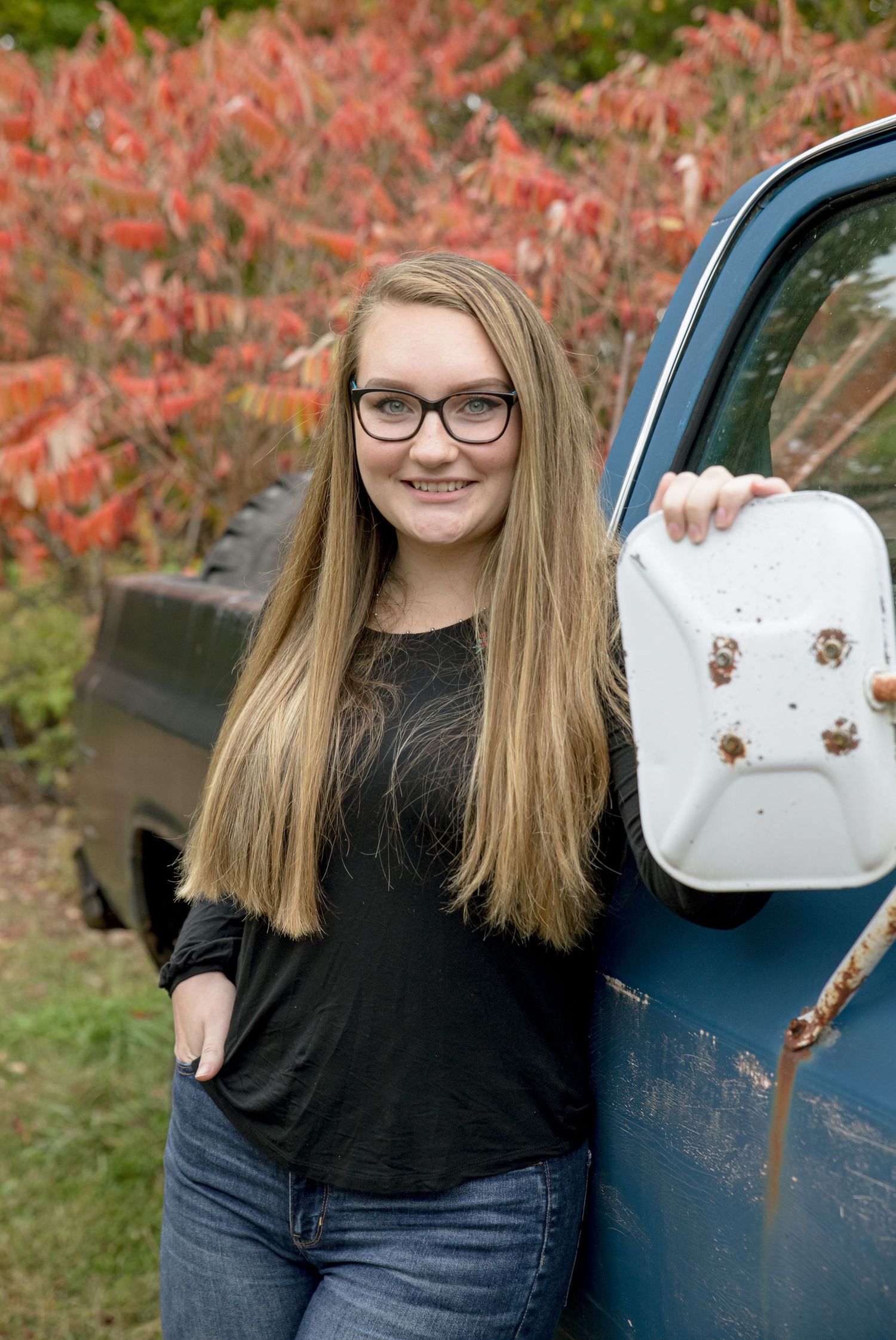 NH High school senior posing for her senior portrait. Fall foliage and small truck Alton NH