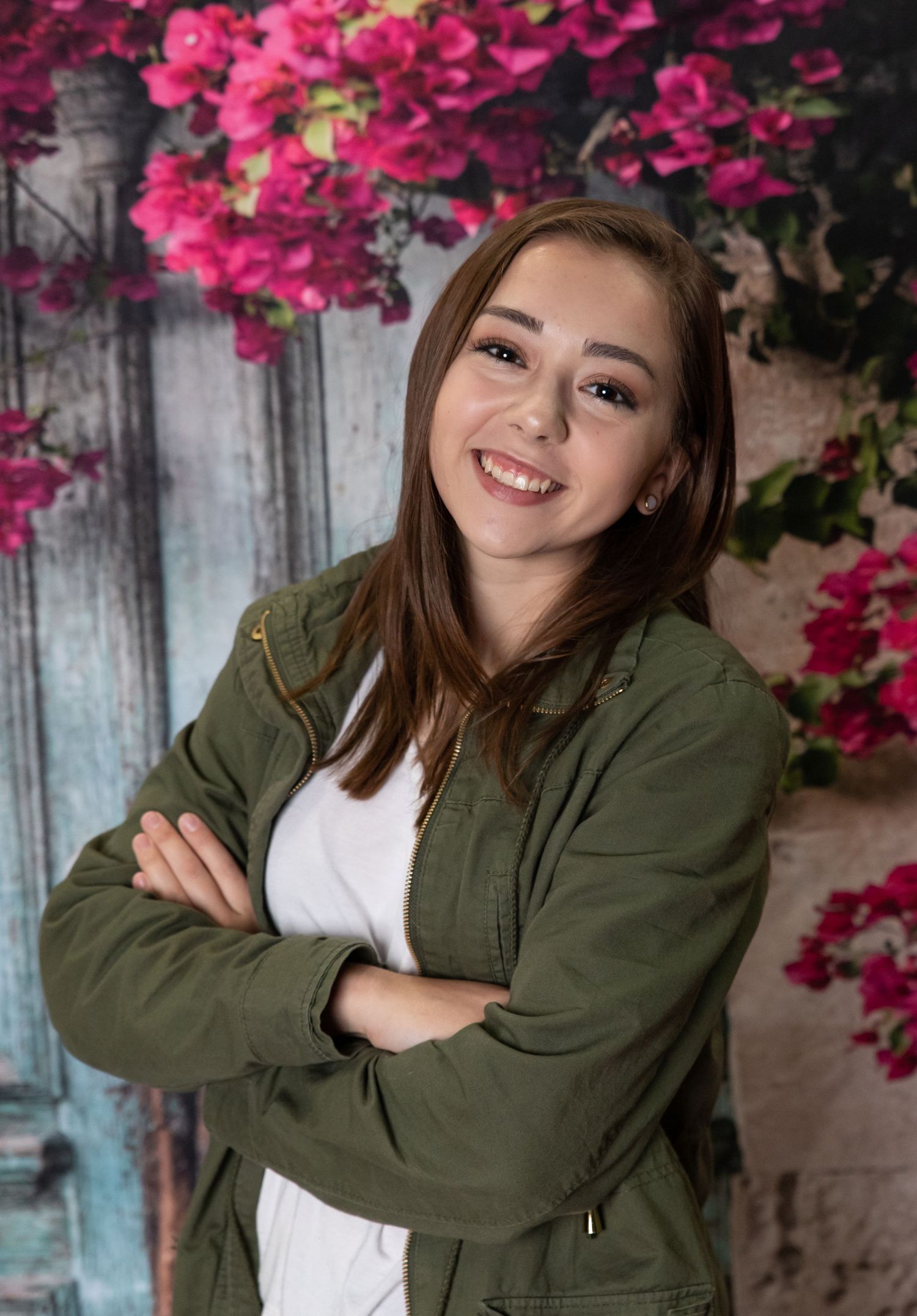 NH High school senior posing for her senior portrait. studio flowered backdrop arms crossed