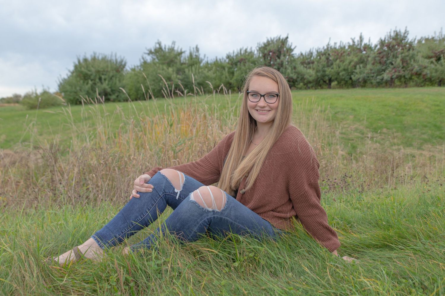 Pittsfield Middle High School senior pictures outside  in the field. brown sweater with holey jeans.