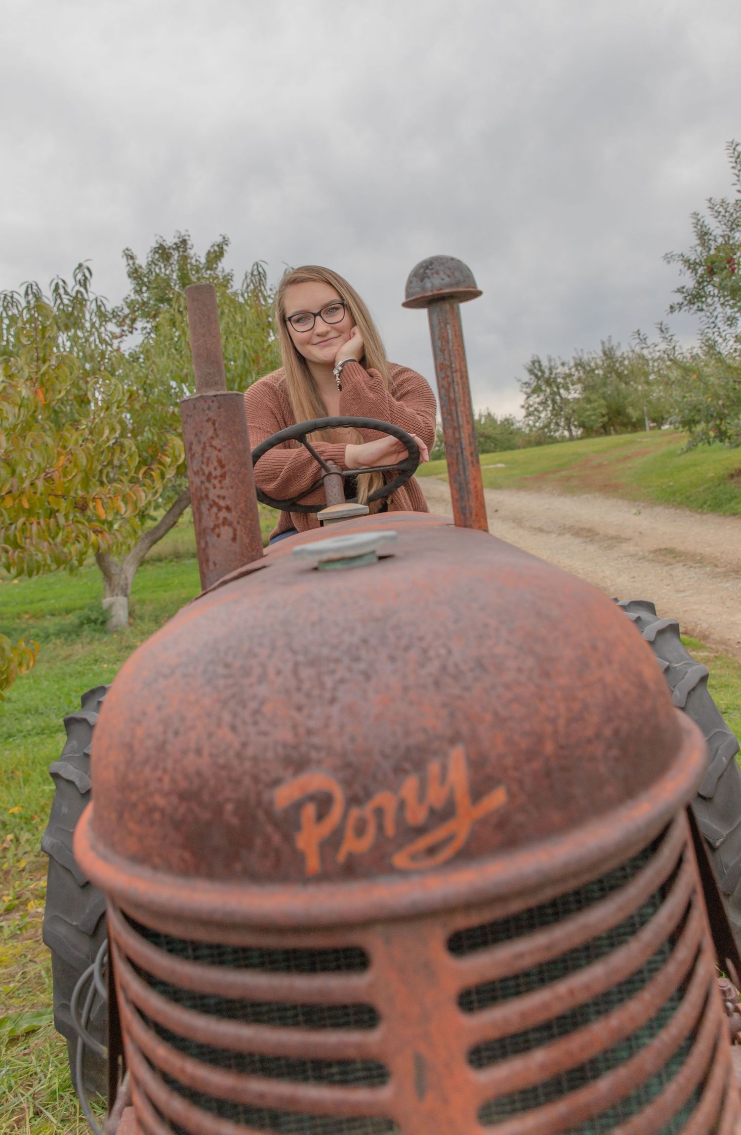 Pittsfield Middle High School senior pictures outside driving a farm tractor in the orchard.