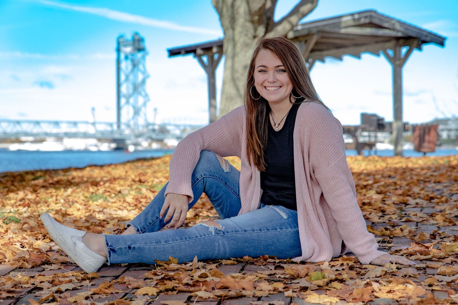 Girl in her senior portrait photr shoot at Prescott park in Portsmouth NH river and bridge in back ground.