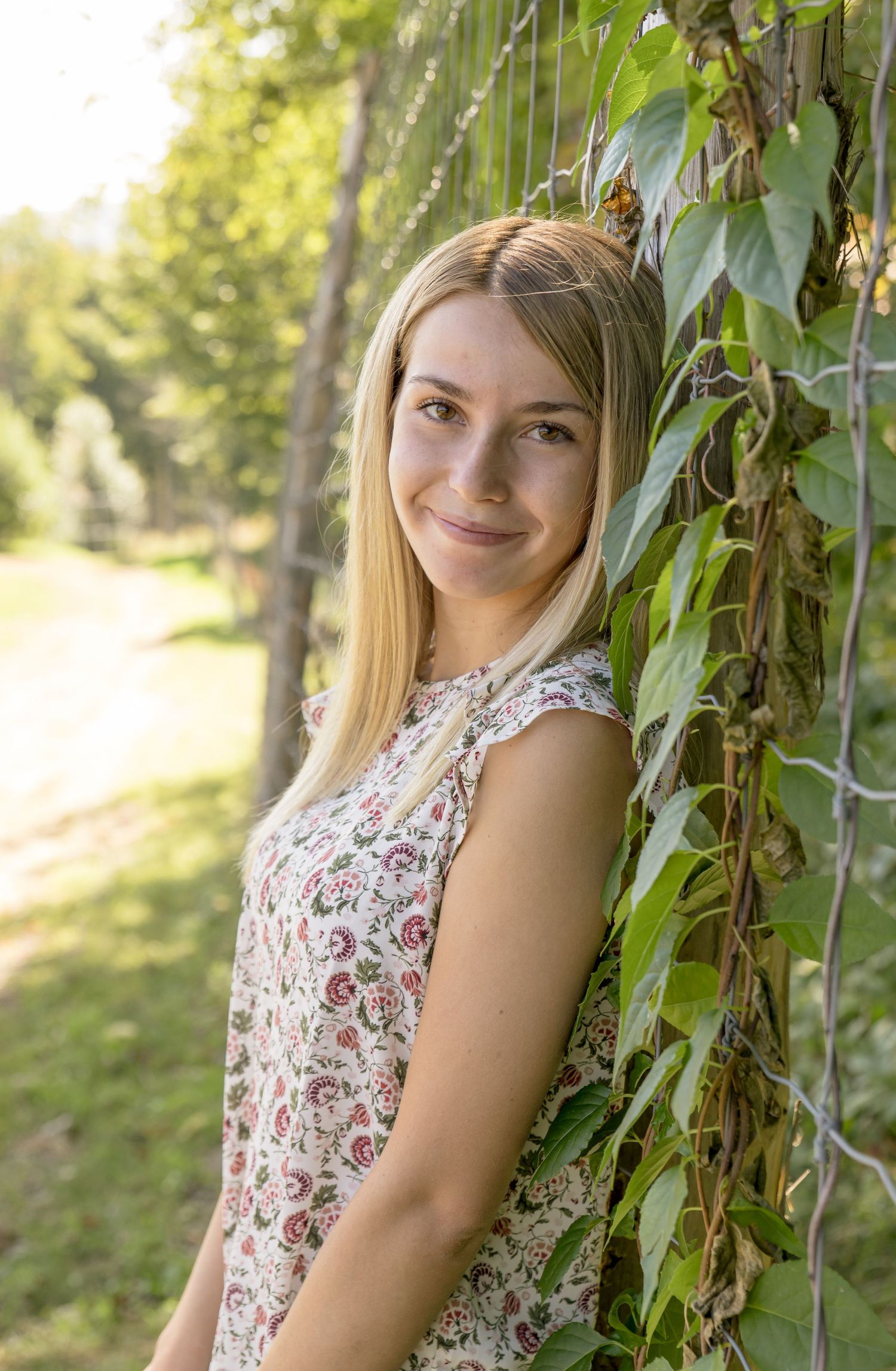 high school senior pictures girl leaning on a plant covered wall blond hair flowered shirt loudon nh