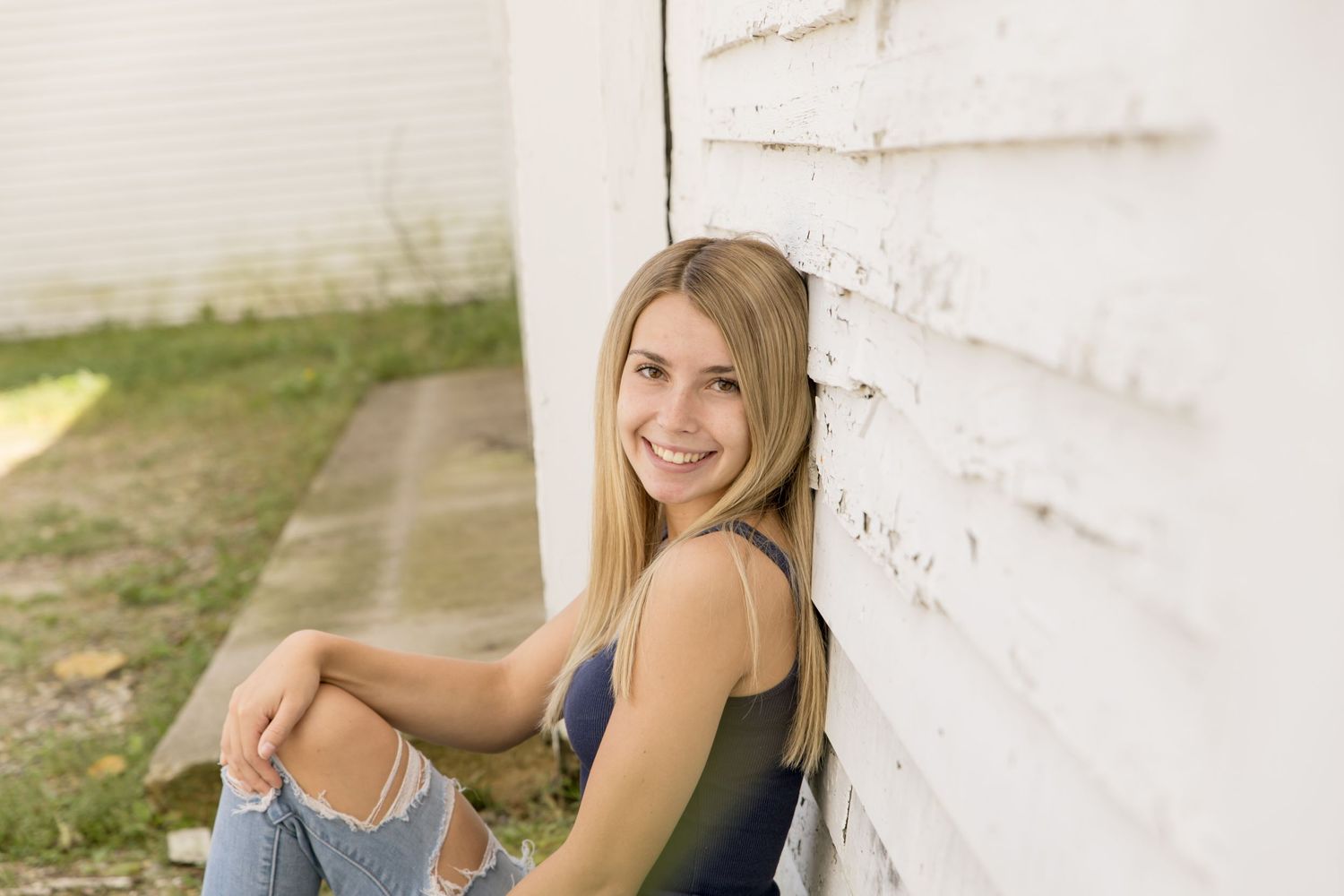 senior girl leaning on the barn wall in Gilford NH