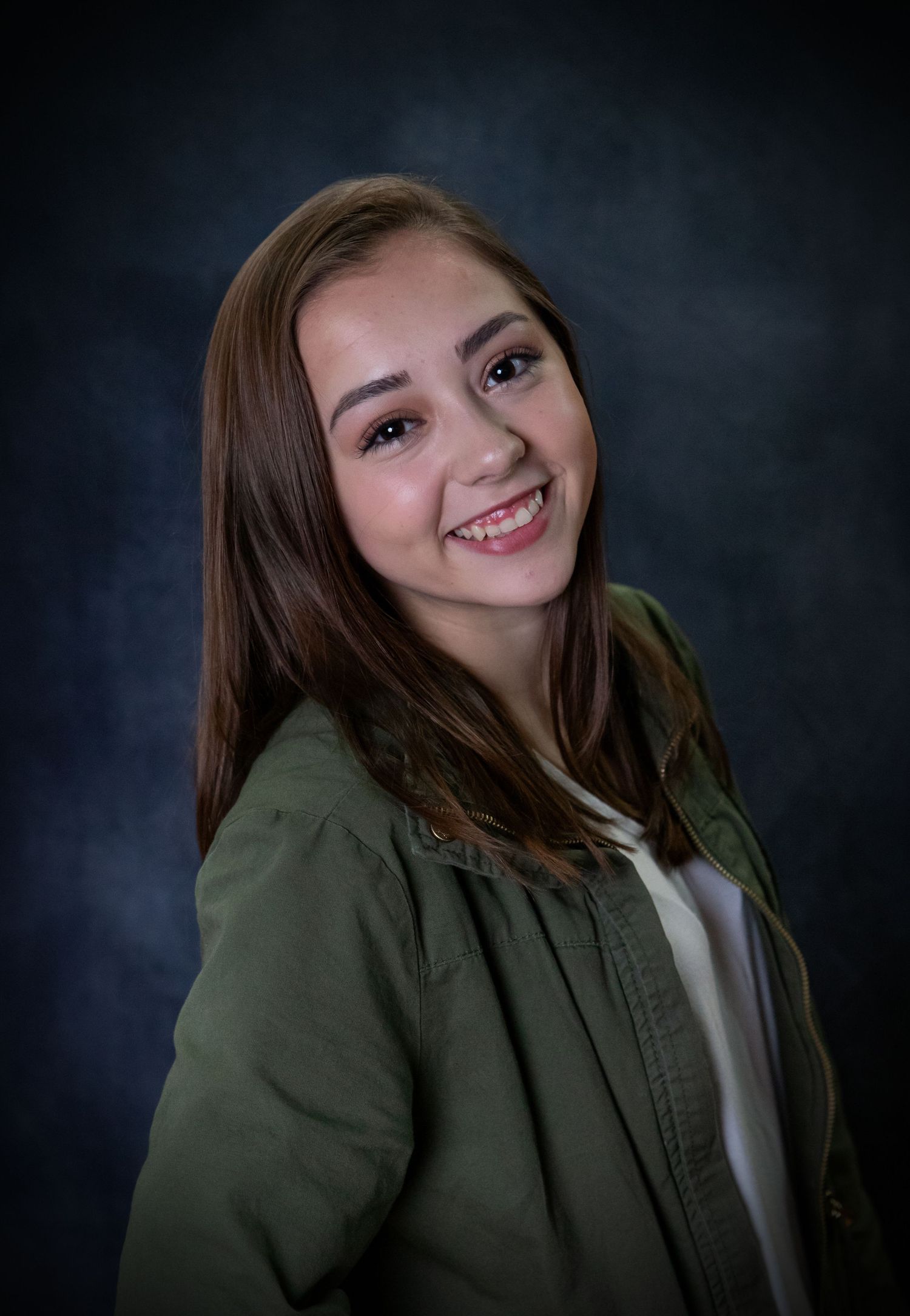 NH High school senior posing for her senior portrait. studio pose leaning back green sweater