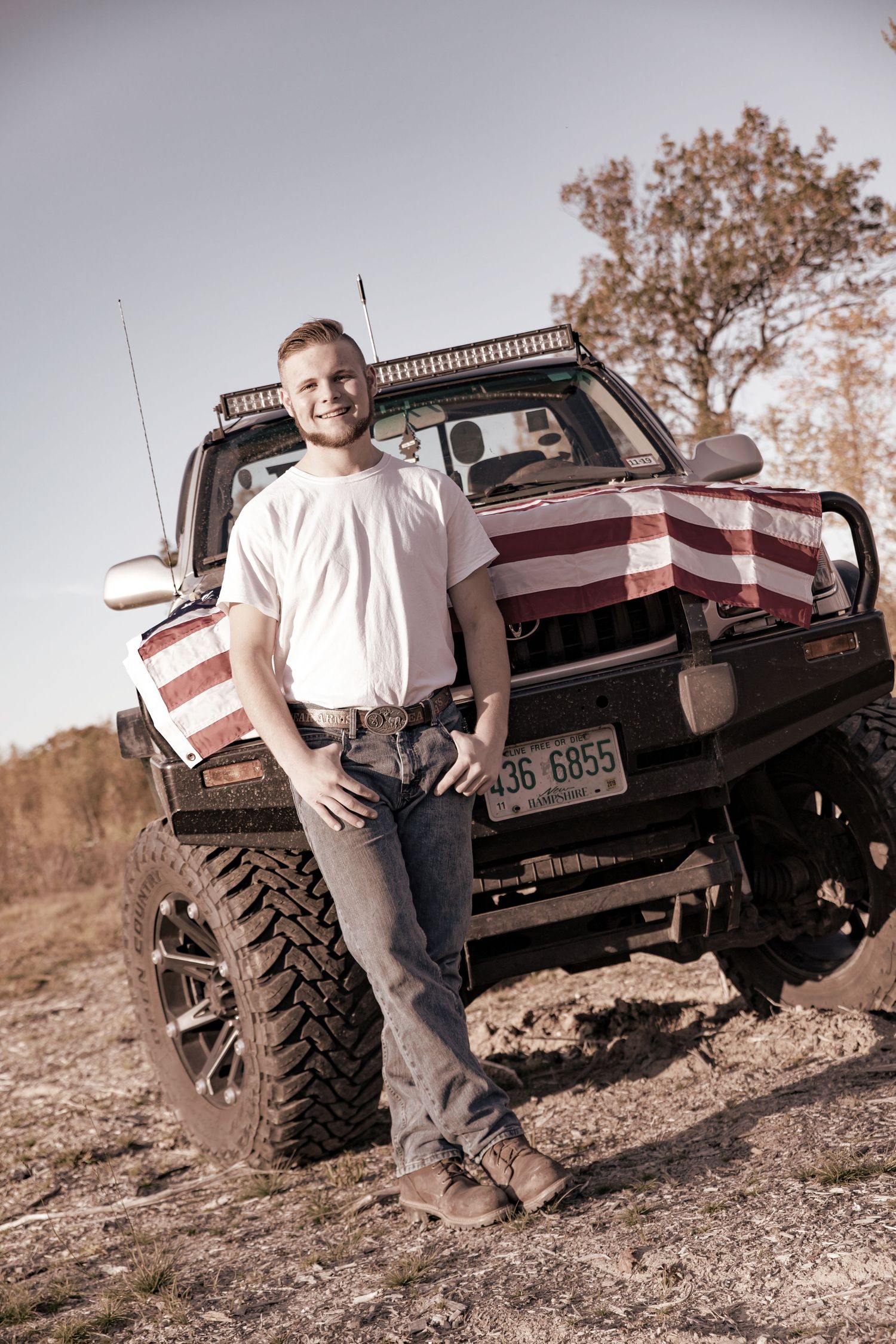 High school boy with his american flag covered truck whit tee jeans  Barnstead NH.