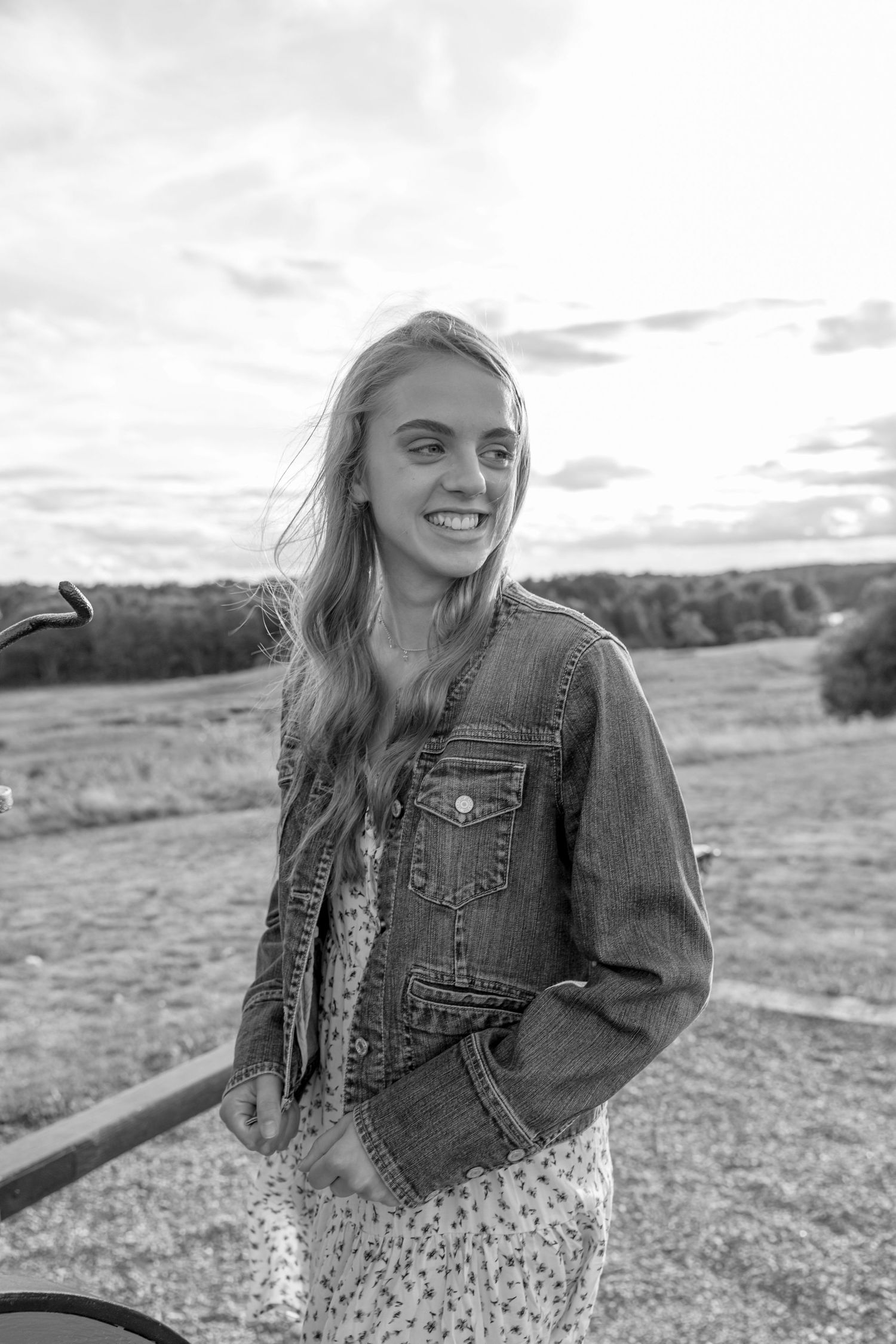 black and white High School  blond girl in field with a dress and jean jacket on