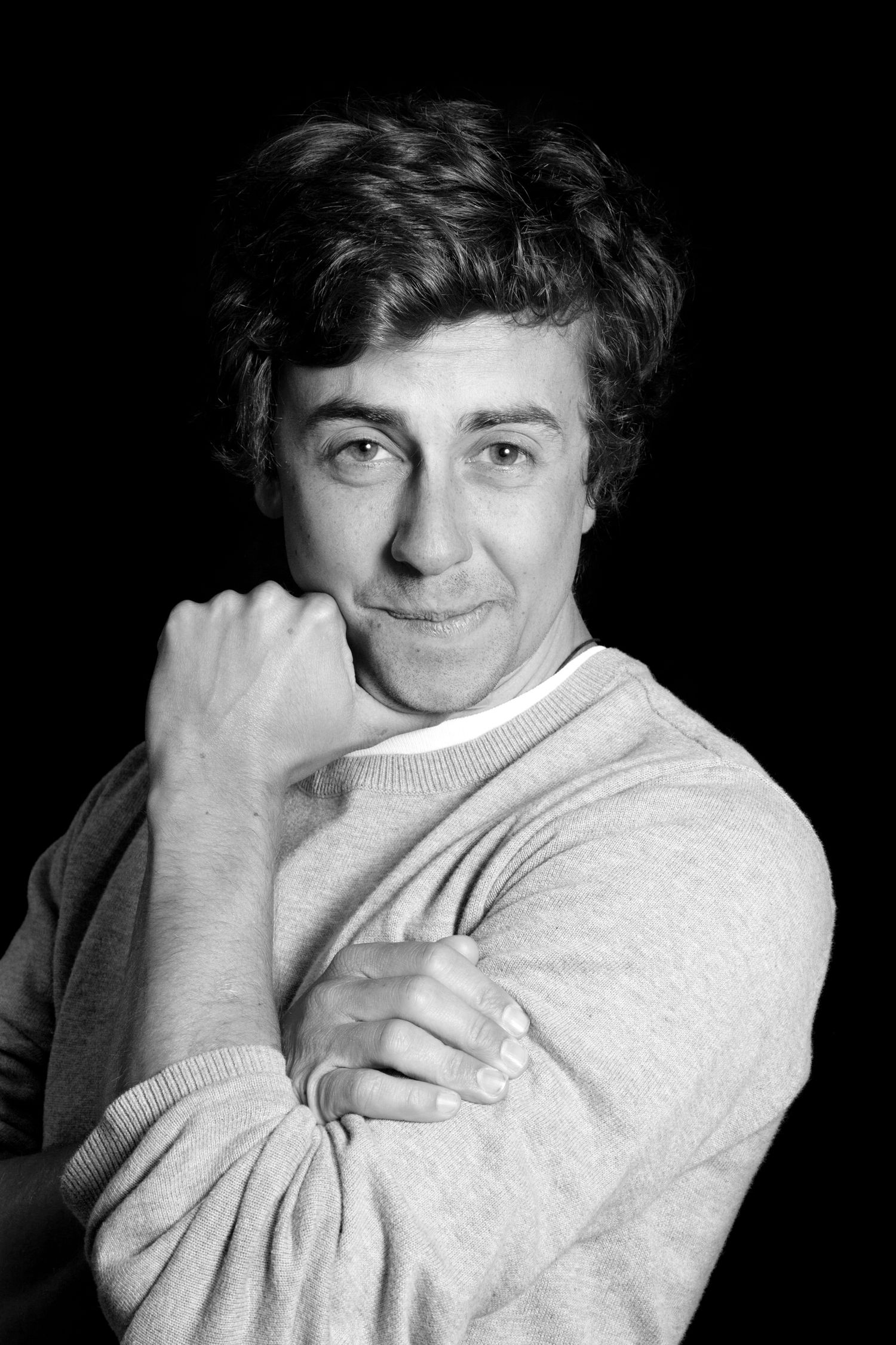 Black and white portrait of a smiling person in a light sweater with their hand near their face during business branding photoshoot.