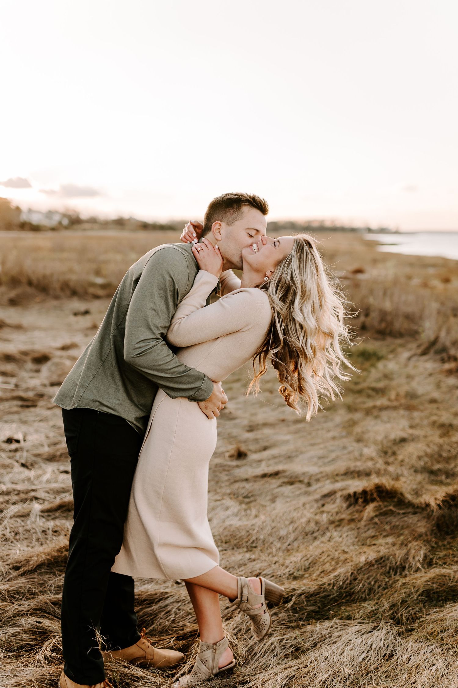 Romantic couple embraces in a golden field at sunset creating an intimate moment.