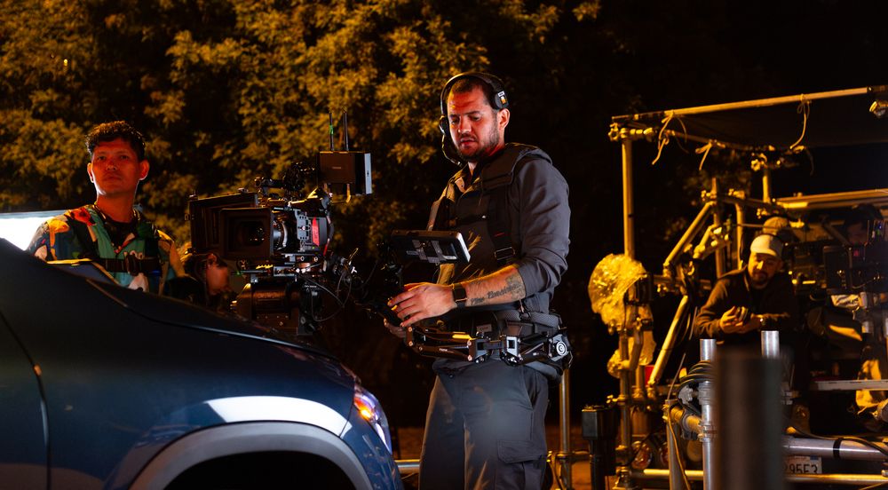 Film crew working with camera equipment during nighttime outdoor shoot.