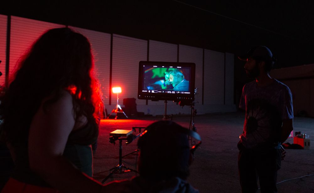 People watching a screen in a dimly lit room with red ambient lighting.