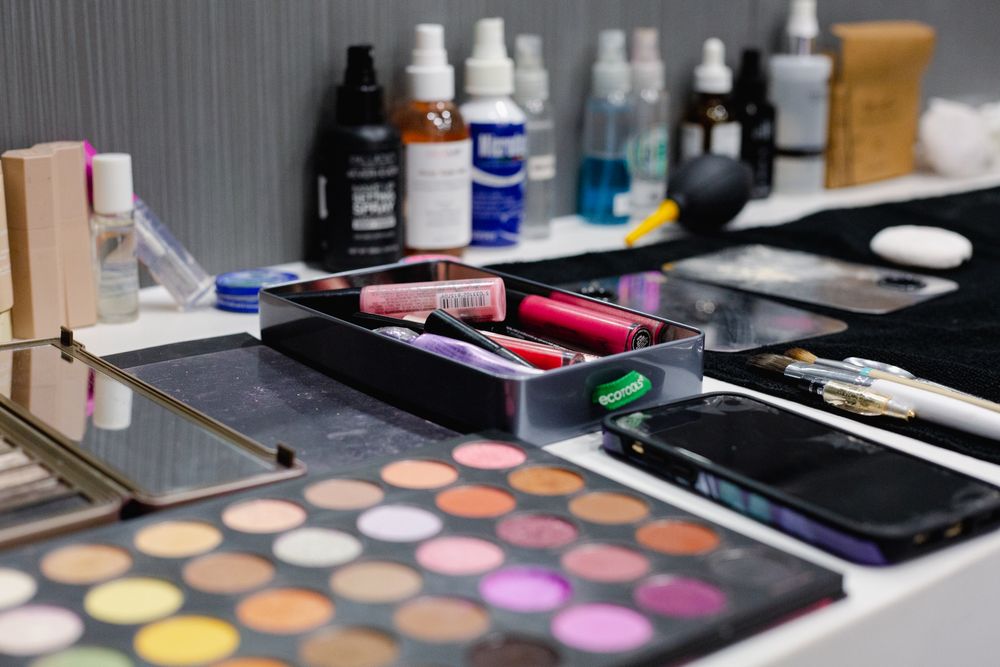 Colorful makeup palettes and beauty products arranged on a gray counter.