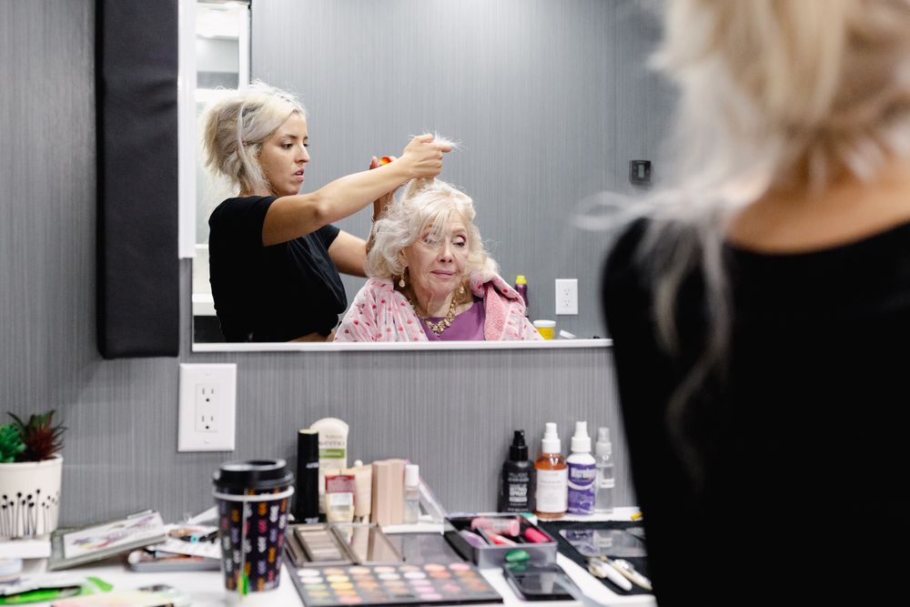 Hair styling session in progress at a well-lit salon mirror station.