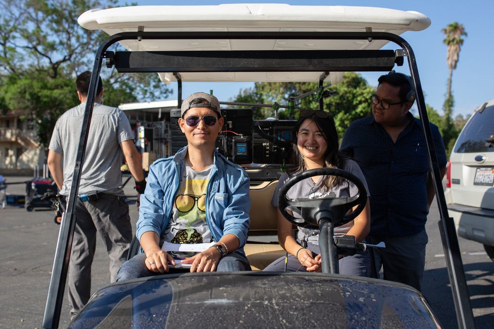 Passengers smiling while seated in a golf cart on a sunny day with palm trees in the background.