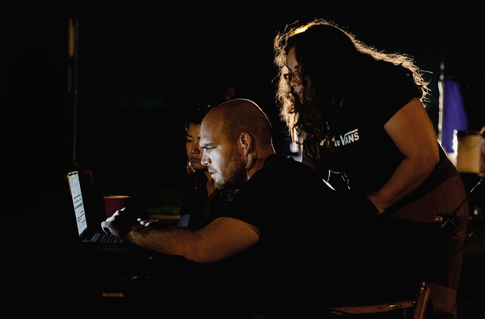 Film production crew working in dark silhouettes against studio lighting.