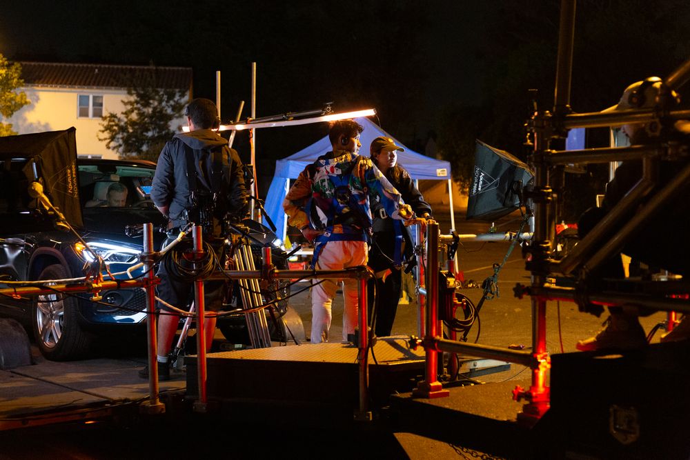 Production team setting up equipment and lights for nighttime filming.