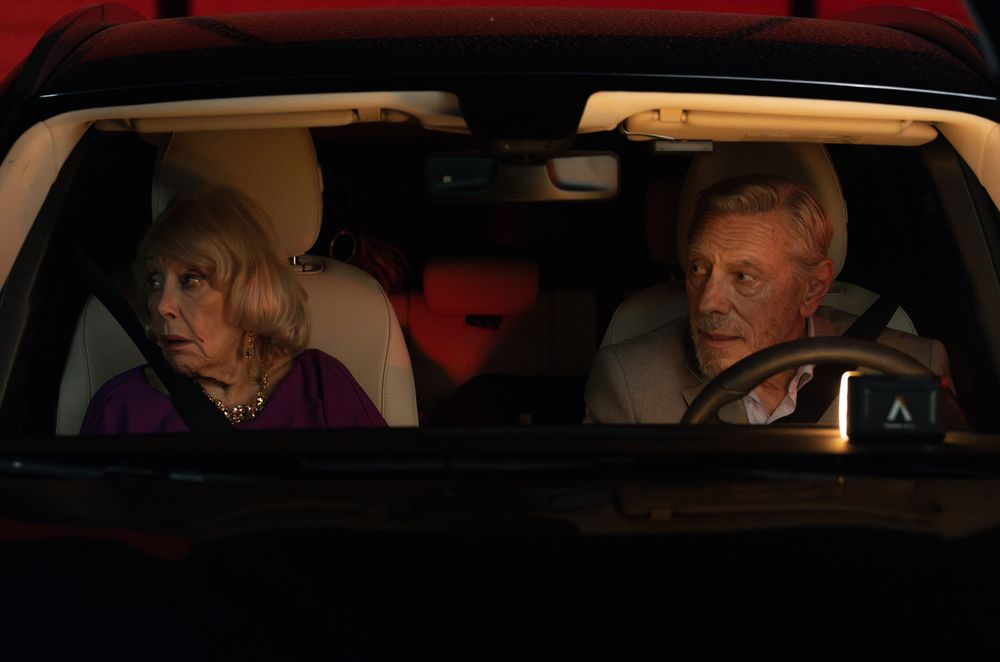 Several silhouettes of people sitting inside a dimly lit car interior.