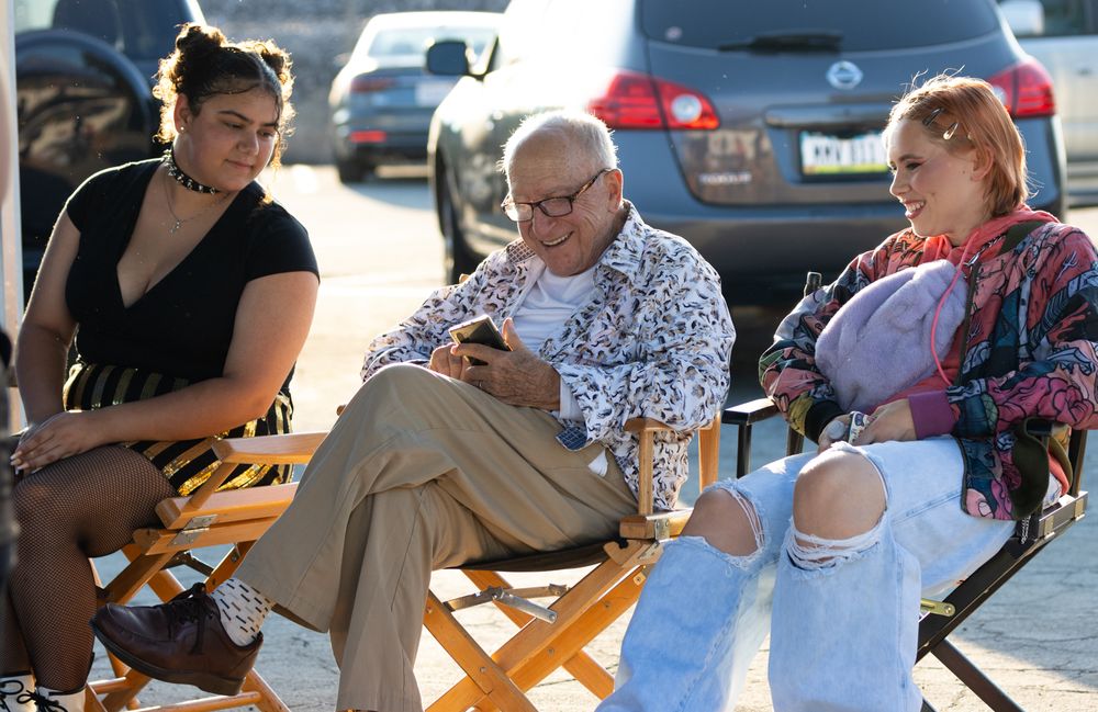 People seated in director-style chairs at an outdoor event.