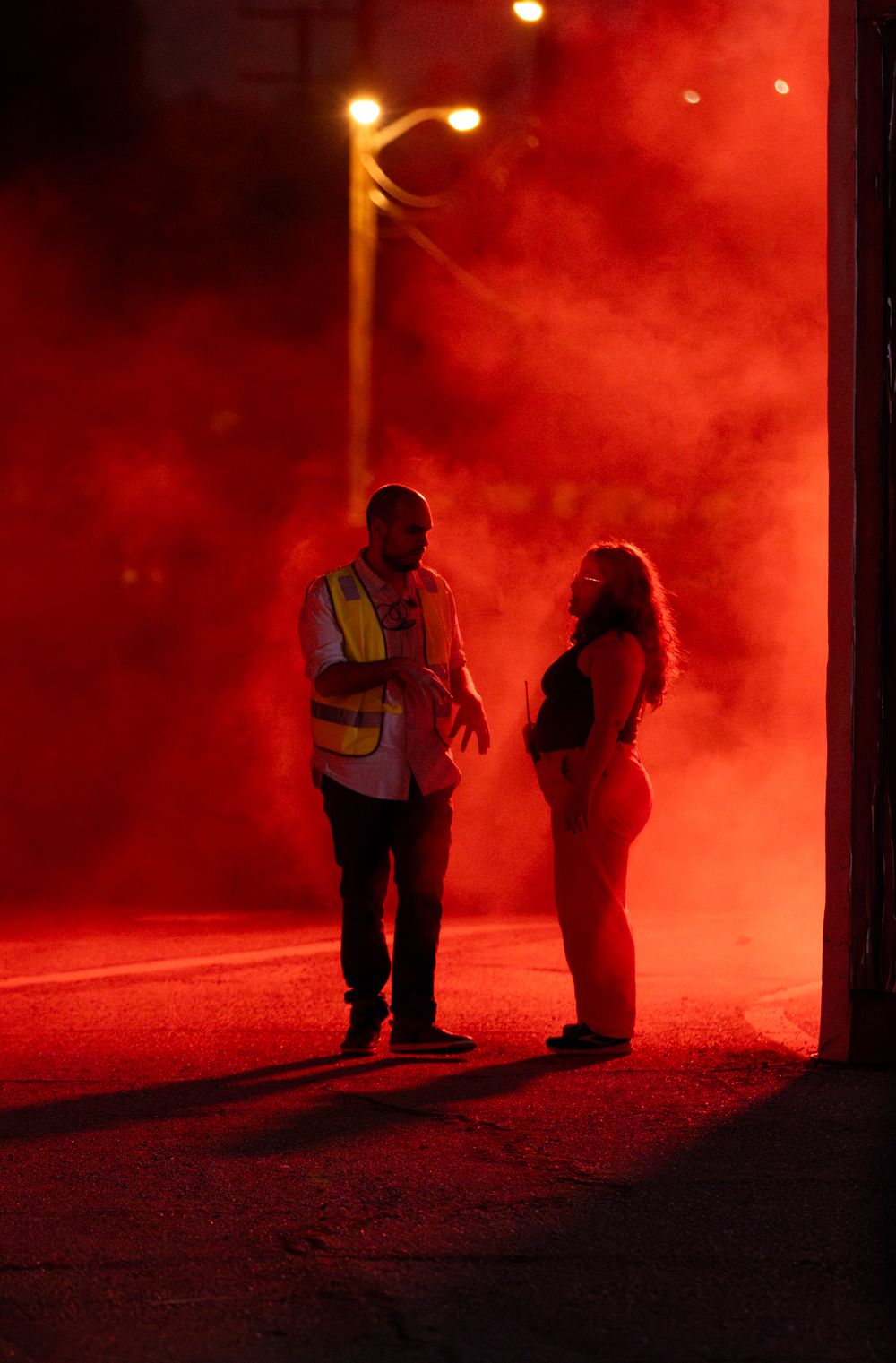 People standing beneath streetlights surrounded by intense red smoke effects.