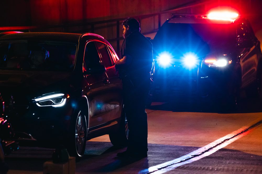 Police vehicles illuminate a nighttime scene with red and blue emergency lights during a traffic stop.