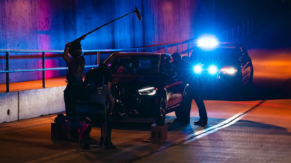 Blue and red police lights create dramatic lighting effects in a nighttime urban setting.