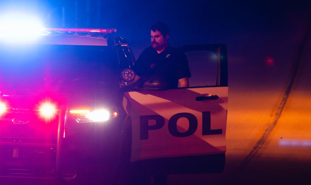 Police emergency lights flash against a dark background during a late night incident.