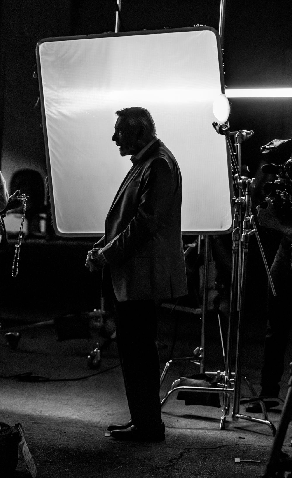 Film production setup with lighting equipment and silhouettes against a white backdrop.