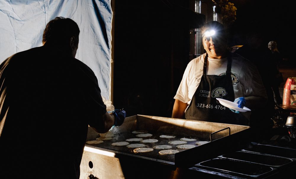 Film crew members setting up lighting and camera equipment in a dark studio environment.