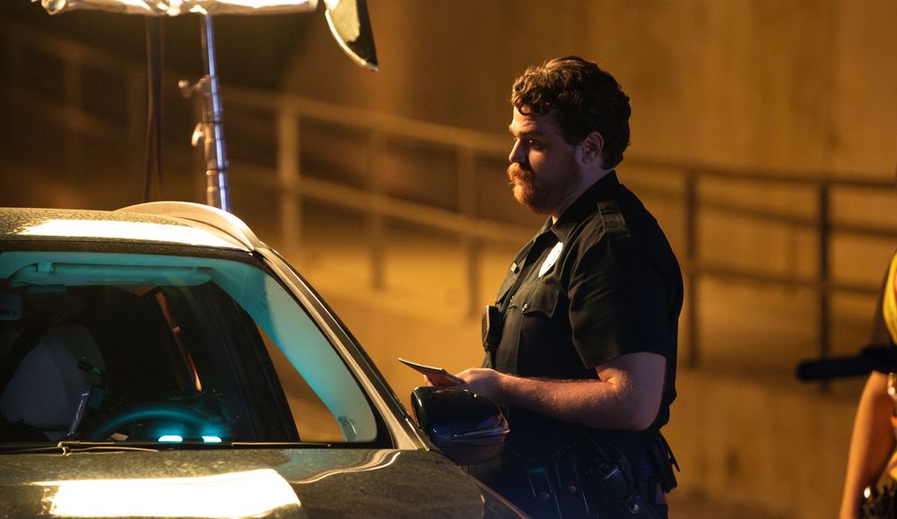 Law enforcement officer conducts paperwork during nighttime traffic stop.
