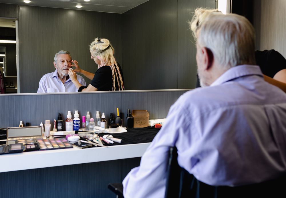 Professional makeup station with bright lighting and mirrors in a modern studio setting.