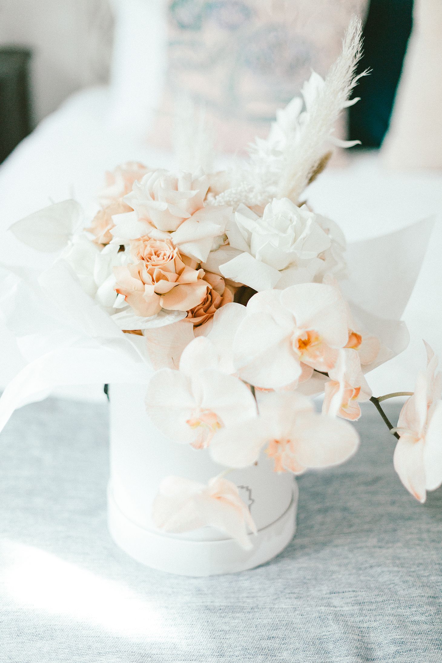 Delicate floral arrangement with white orchids and peach roses in a white vase.