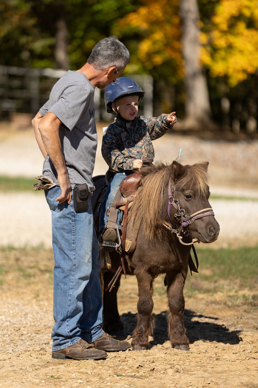 A young boy sitting on his pony going over the next course with an older man.