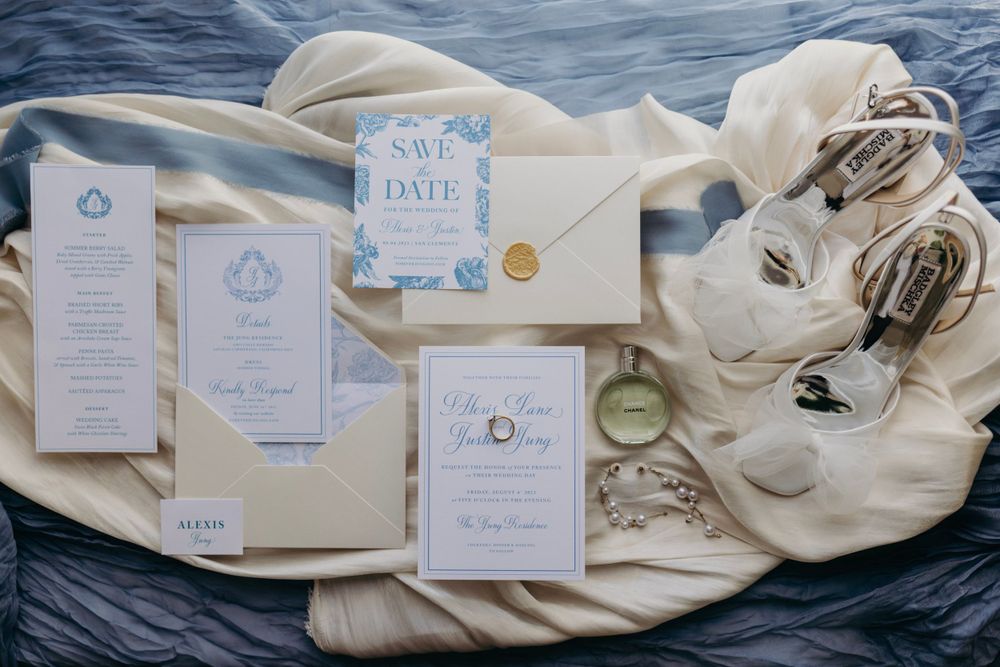Wedding invitation suite with blue and white stationery displayed on fabric.