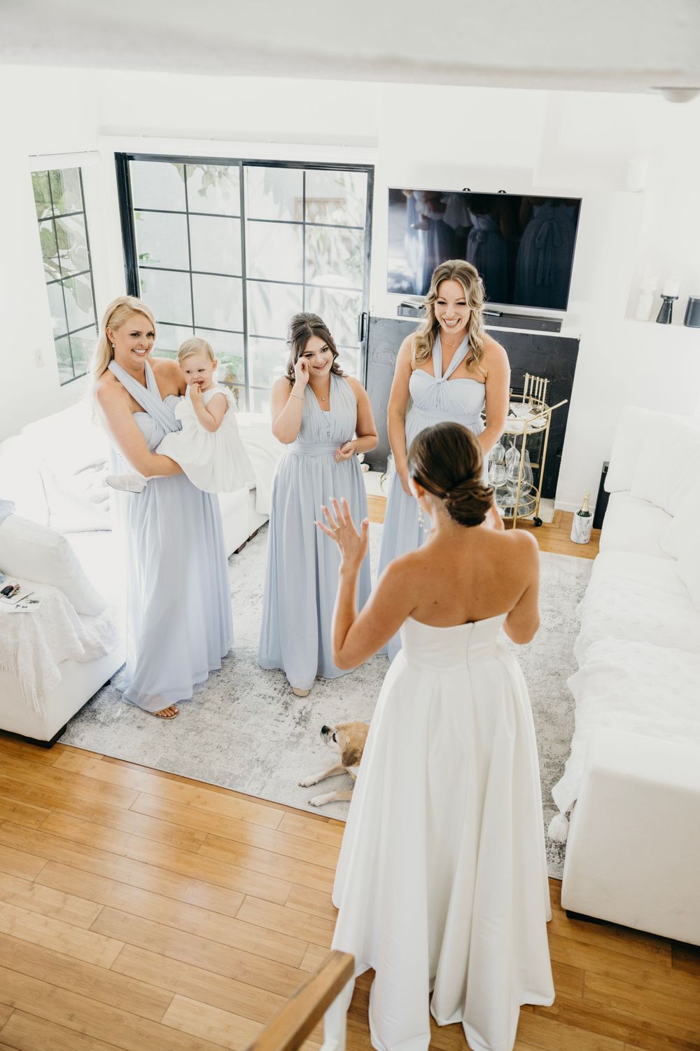 Wedding party members in light blue dresses react emotionally during pre-ceremony preparations.