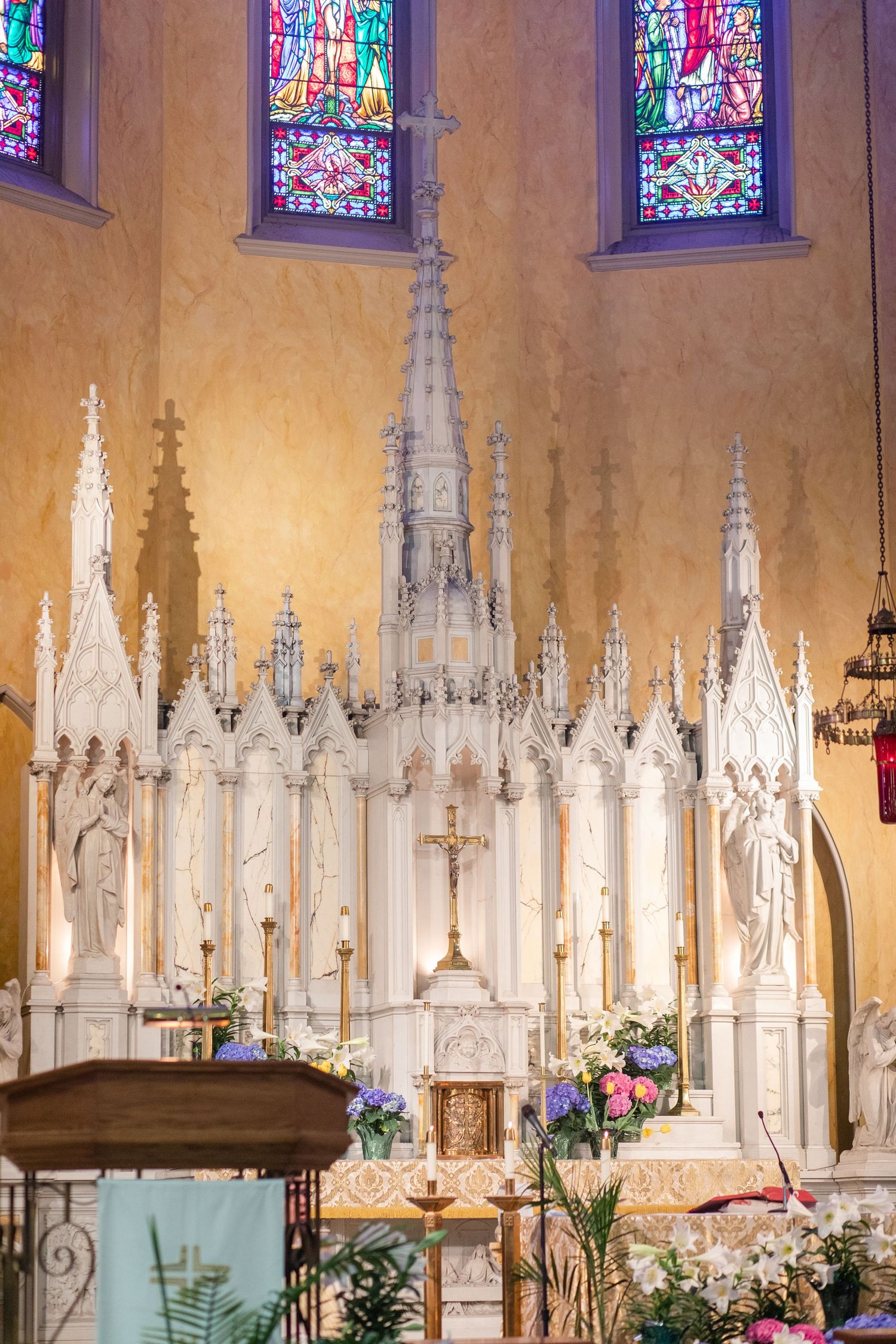 Stunning church interior with gothic architecture, white altar, and colorful stained glass windows.