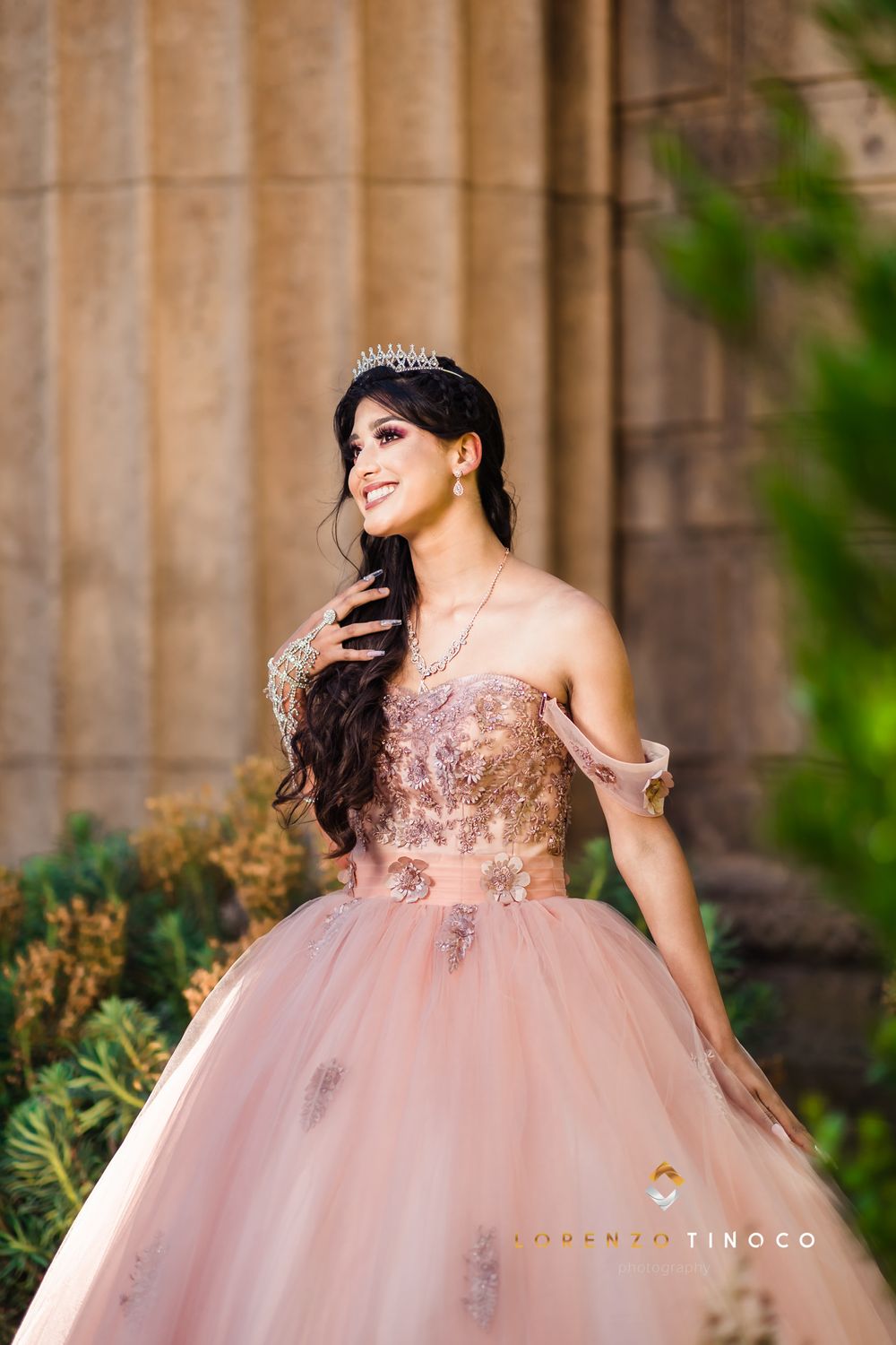 An elegant pink quinceanera dress with beaded bodice photographed in front of stone architecture.