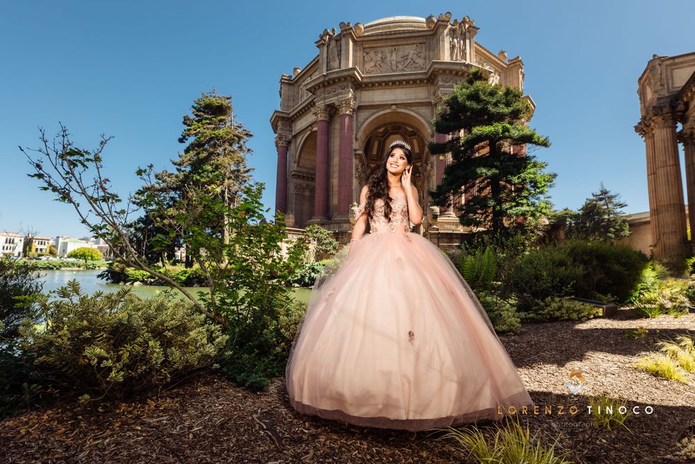 Wide shot of woman in pink ballgown posing in front of domed classical architecture.