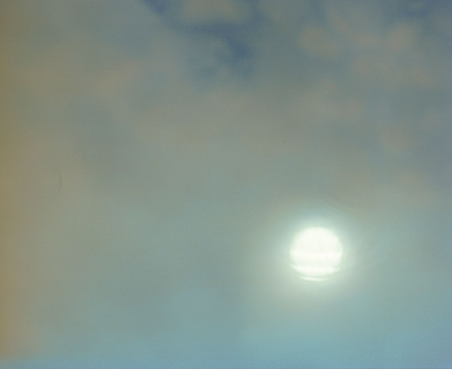 Soft clouds in a pale blue sky with diffused sunlight creating a dreamy atmospheric effect.