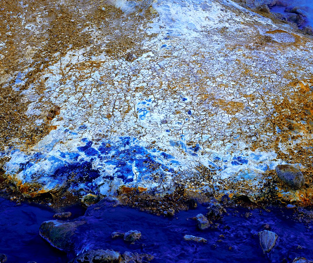Aerial view of coastline with vibrant blue water and golden brown terrain patterns.