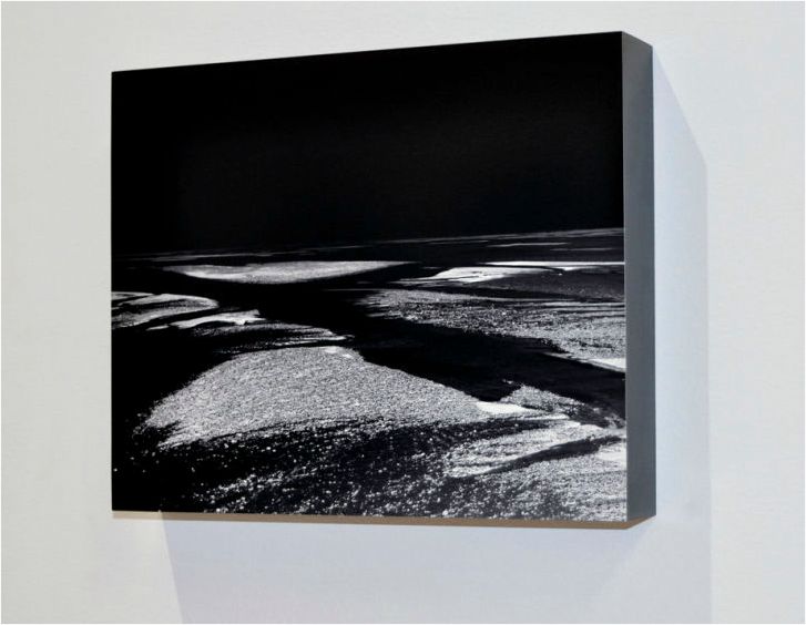 Minimalist gallery wall displaying black and white landscape photographs in a clean white space.