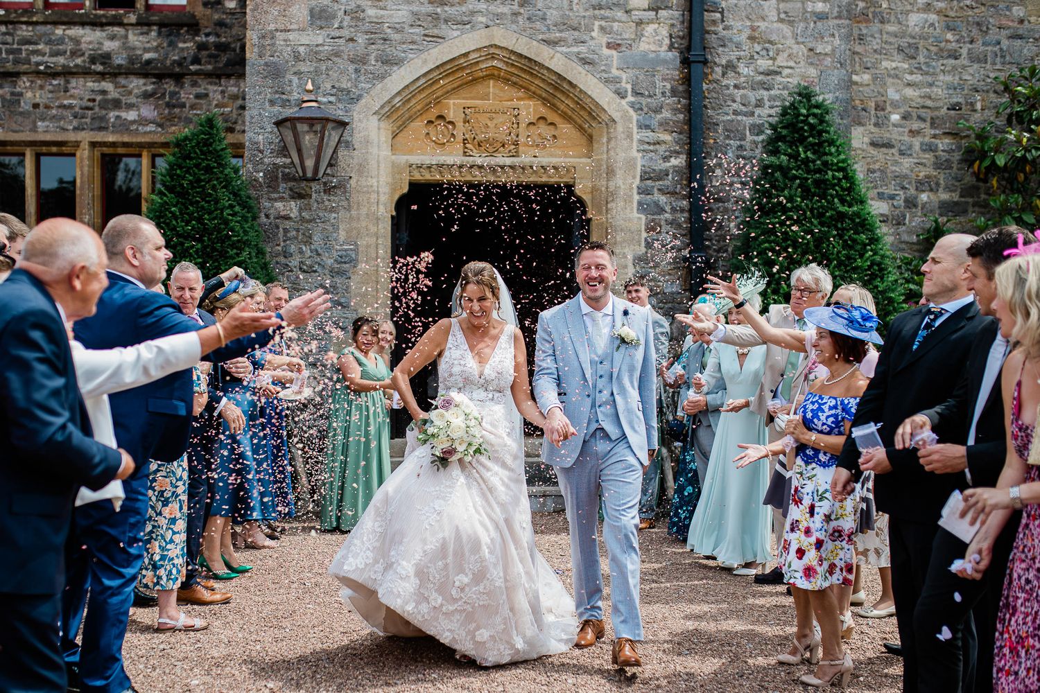 Wedding guests throw confetti on a newly wed couple, at Huntsham Court wedding venue in Devon.