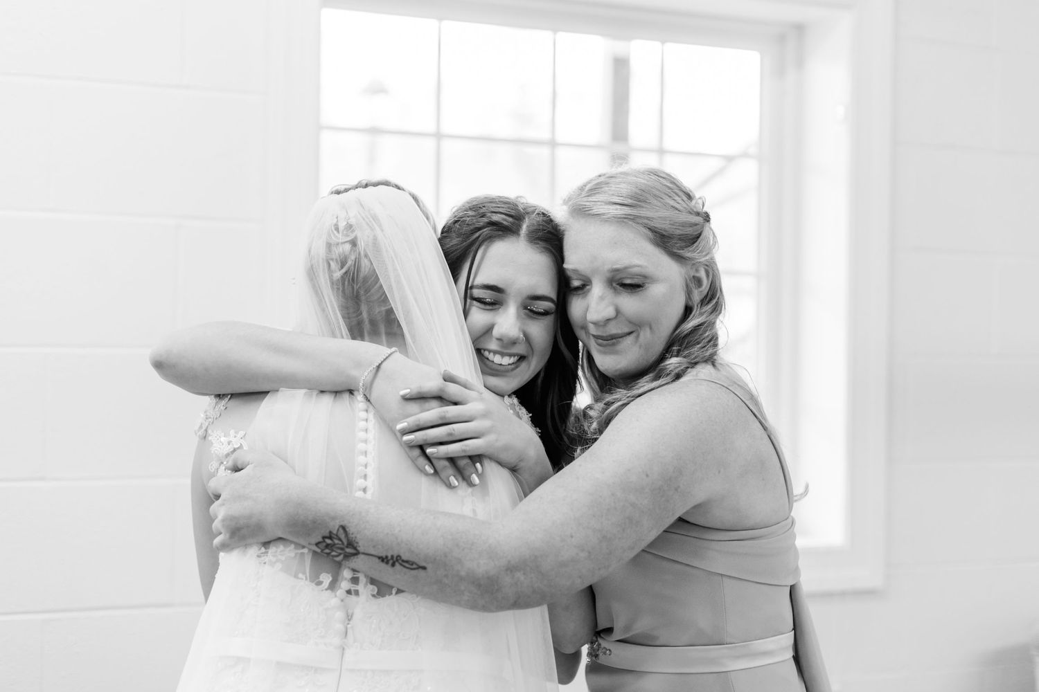 Black and white photo captures tender moments between wedding party members.