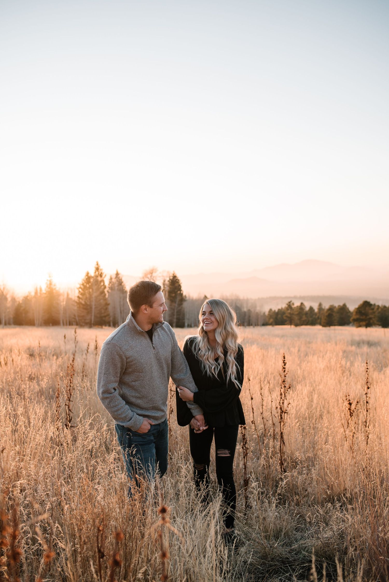 Couple sharing joyful moments in a field of dried grass at dusk.