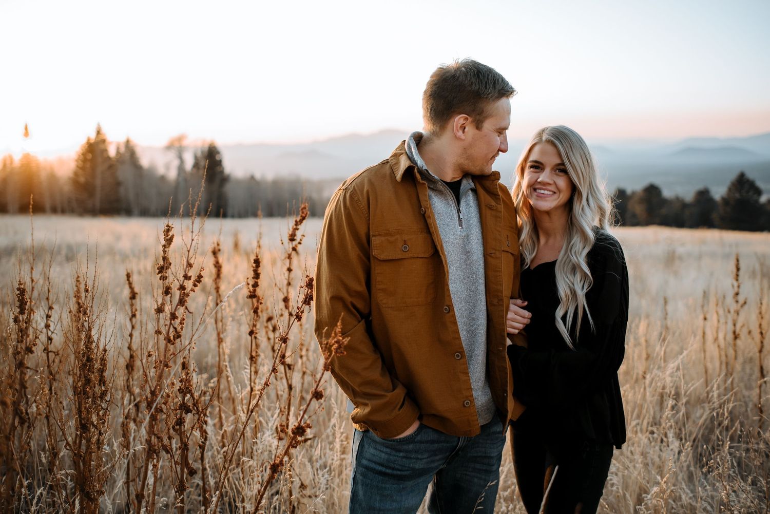 Couple sharing intimate moment in autumn field during golden hour.