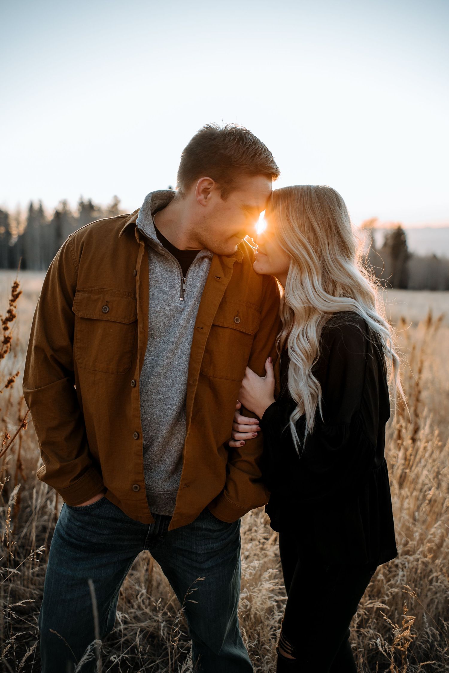 Romantic couple sharing tender moments in a golden wheat field at sunset.